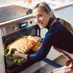 Lachende vrouw haalt gerecht uit de oven